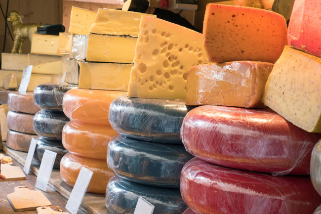 Variety and different types of cheese on stall market shop counter.