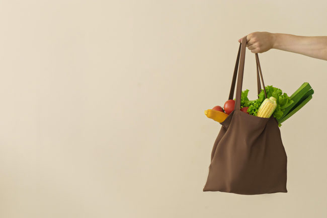 hand holding reusable shopping bag with produce items