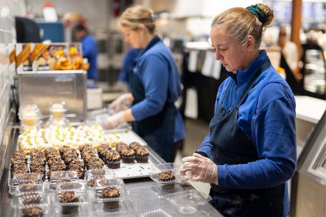 workers preparing packaged cupcakes in a bakery